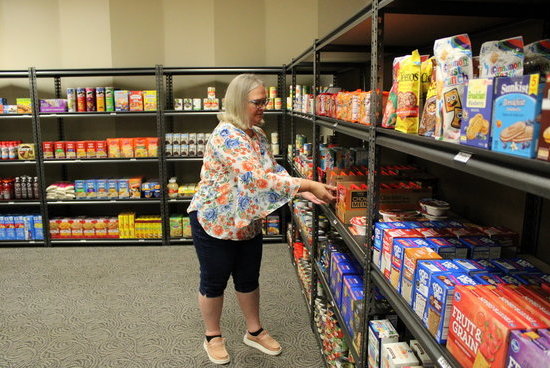 Lisa Coffey stocks the shelves of the newly relocated Pantry for student use. 
